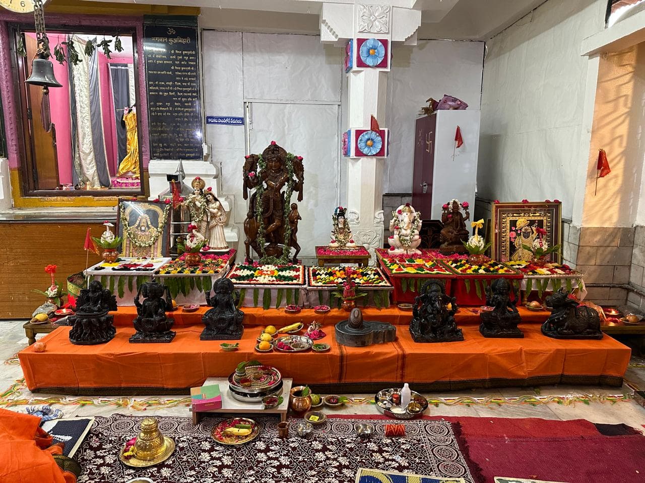 A temple altar arranged with deities, flowers and offerings