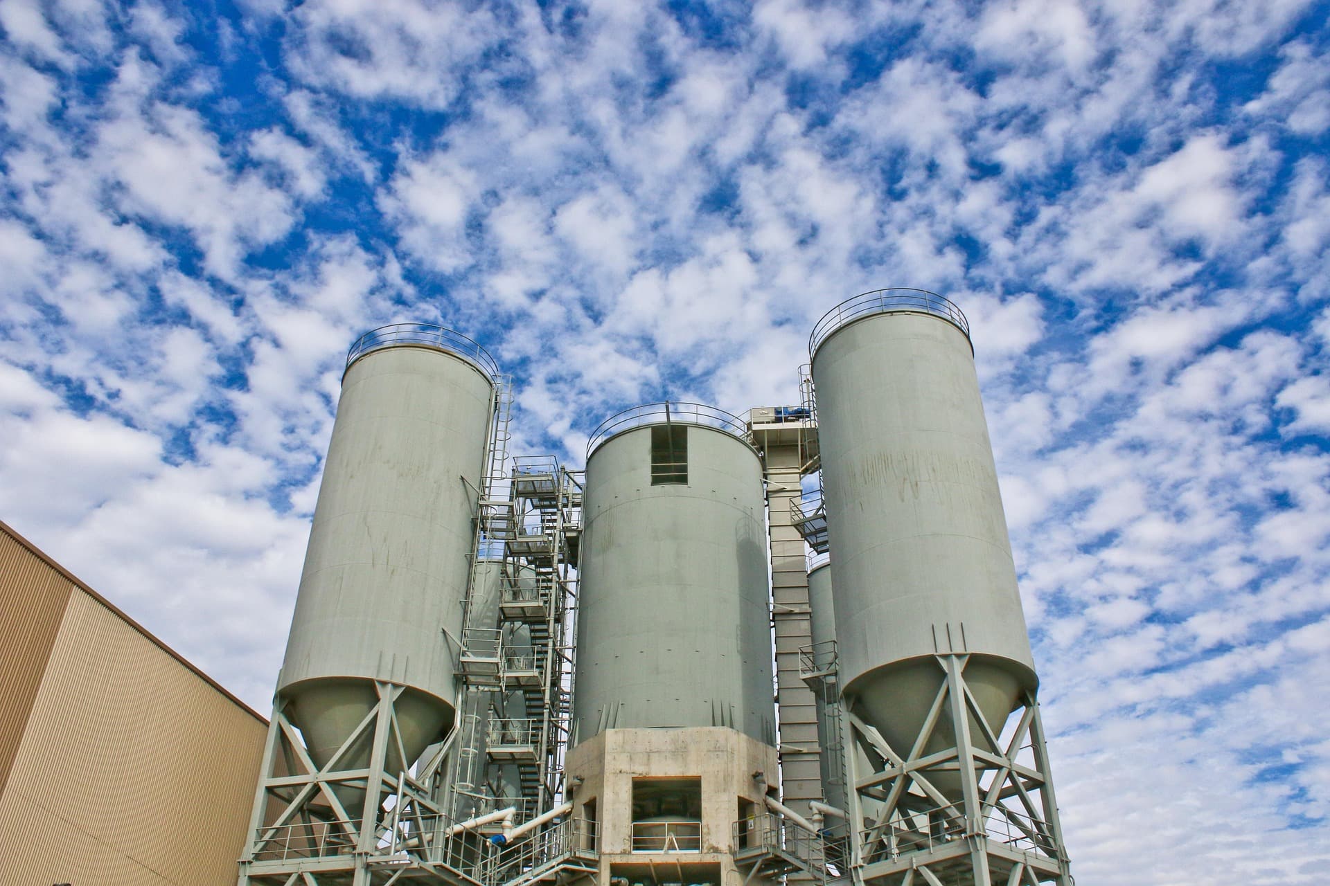 Industrial storage silos and steel access structures against a blue sky
